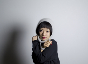 灰色の毛糸の帽子をかぶり、黒い服を着た倉沢 よしえさんの写真