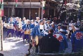背中に「祭り」と書かれた法被を着た人たちが太鼓を担ぎ列を成している祭りの様子の写真