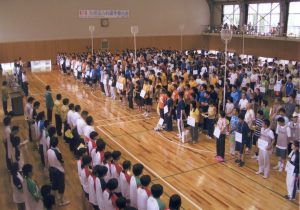 体育館に参加者の選手達や関係者達が整列している写真