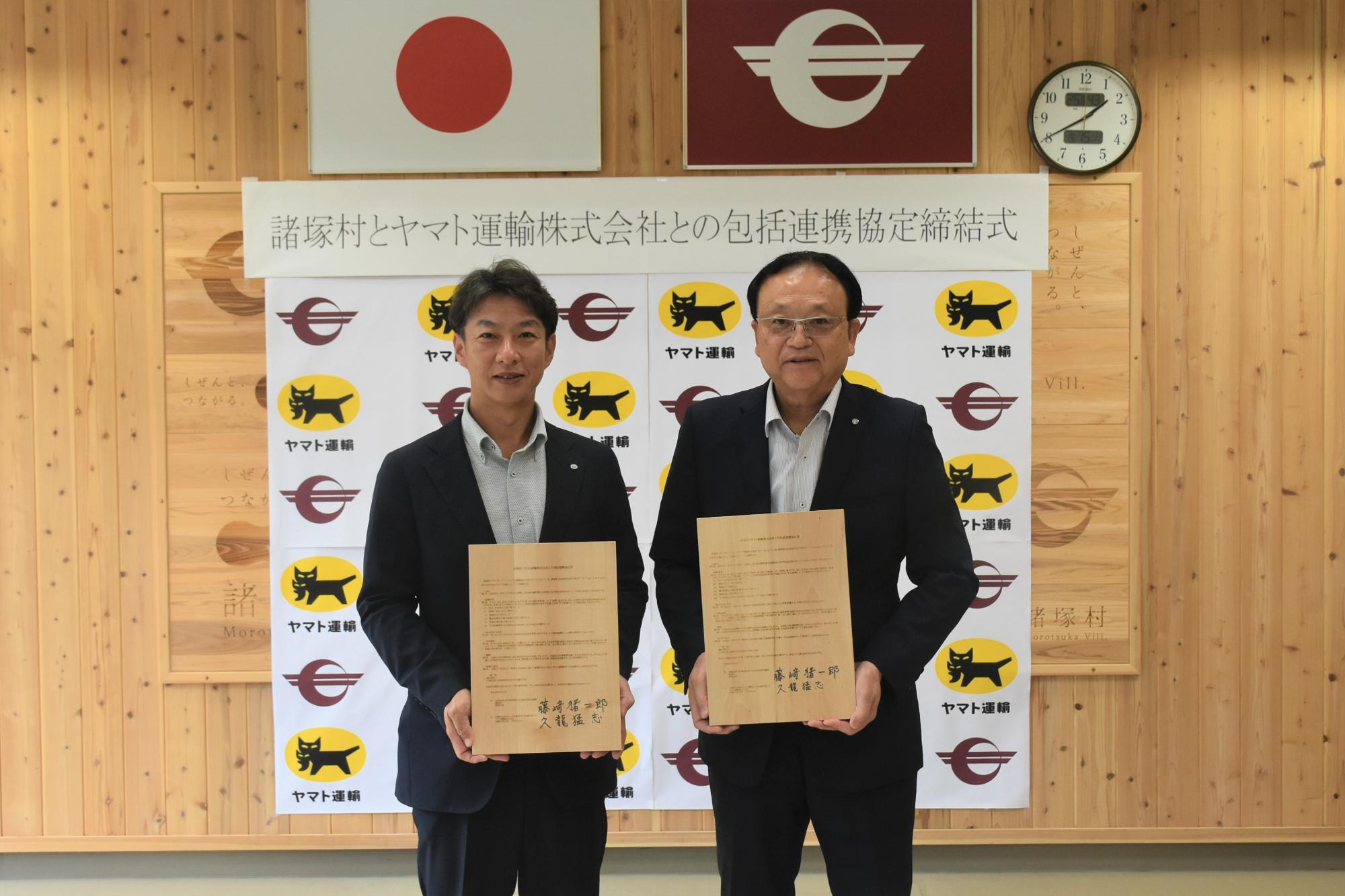 諸塚村長とヤマト運輸株式会社宮崎主管支店長が協定書を持つ写真